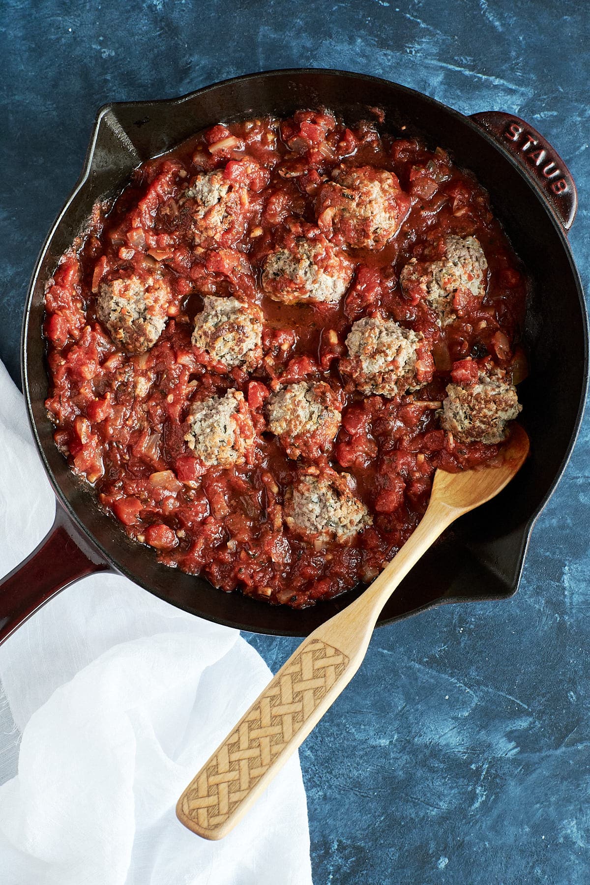 Meatballs made with ricotta and ground beef, topped with red sauce in a sauté pan. 