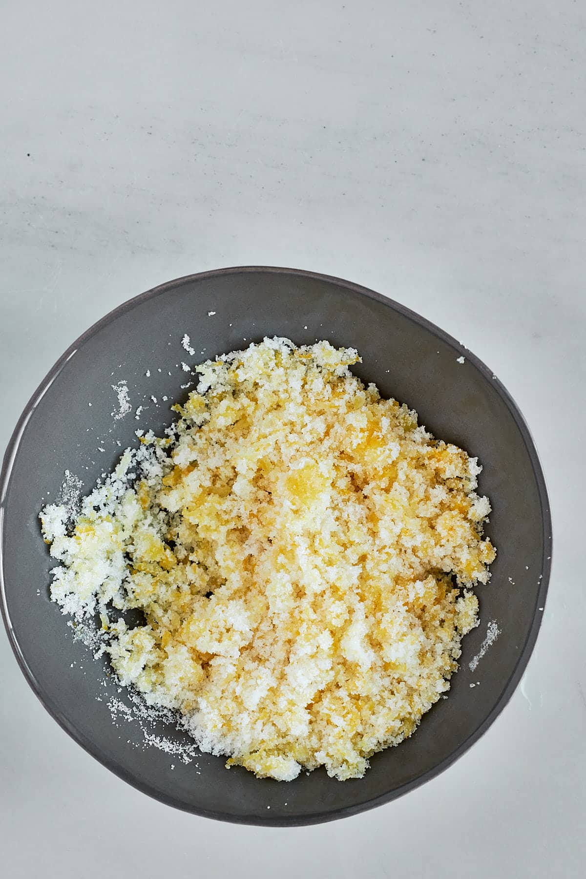 Sugar and lemon zest combined in a small grey bowl