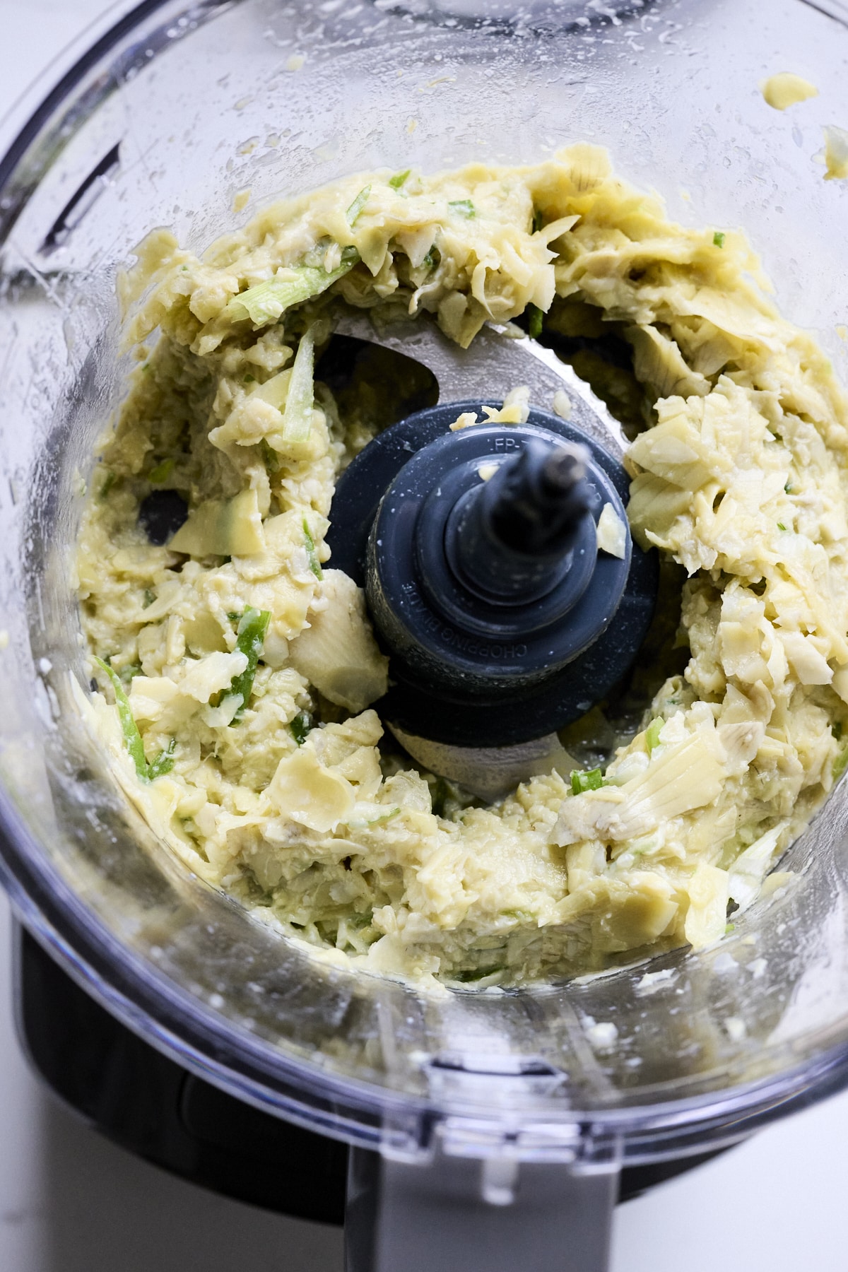 Chopped artichoke hearts in the bowl of a food processor
