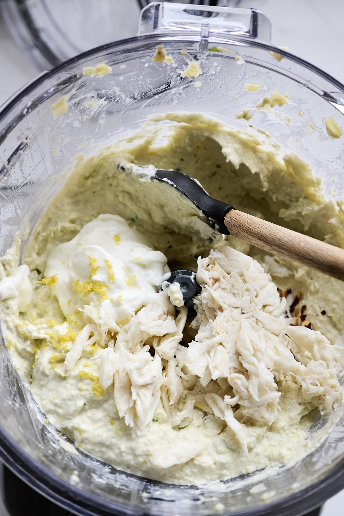 Lump crab meat being stirred into artichoke dip