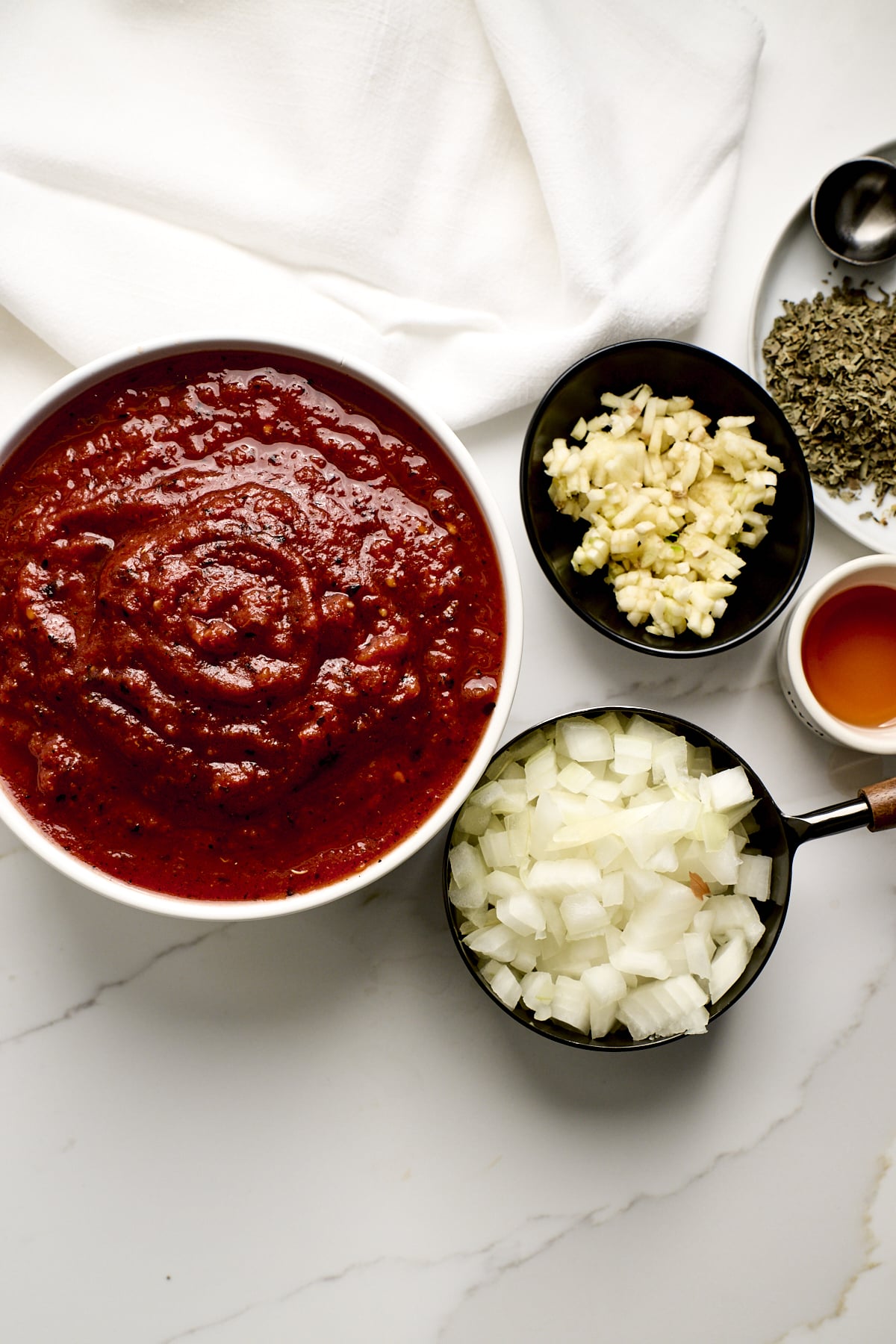 Small bowls of crushed tomatoes, chopped onion + garlic, and dried spices