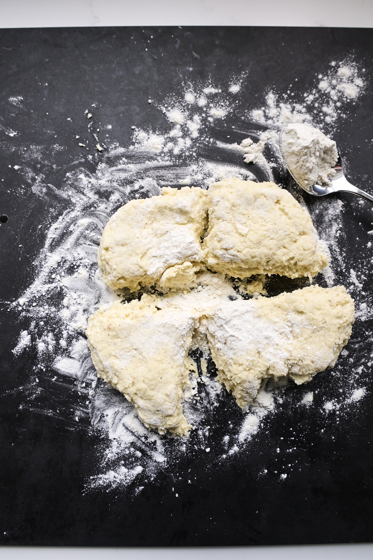 Ricotta gnocchi dough divided into four parts on a dark cutting board