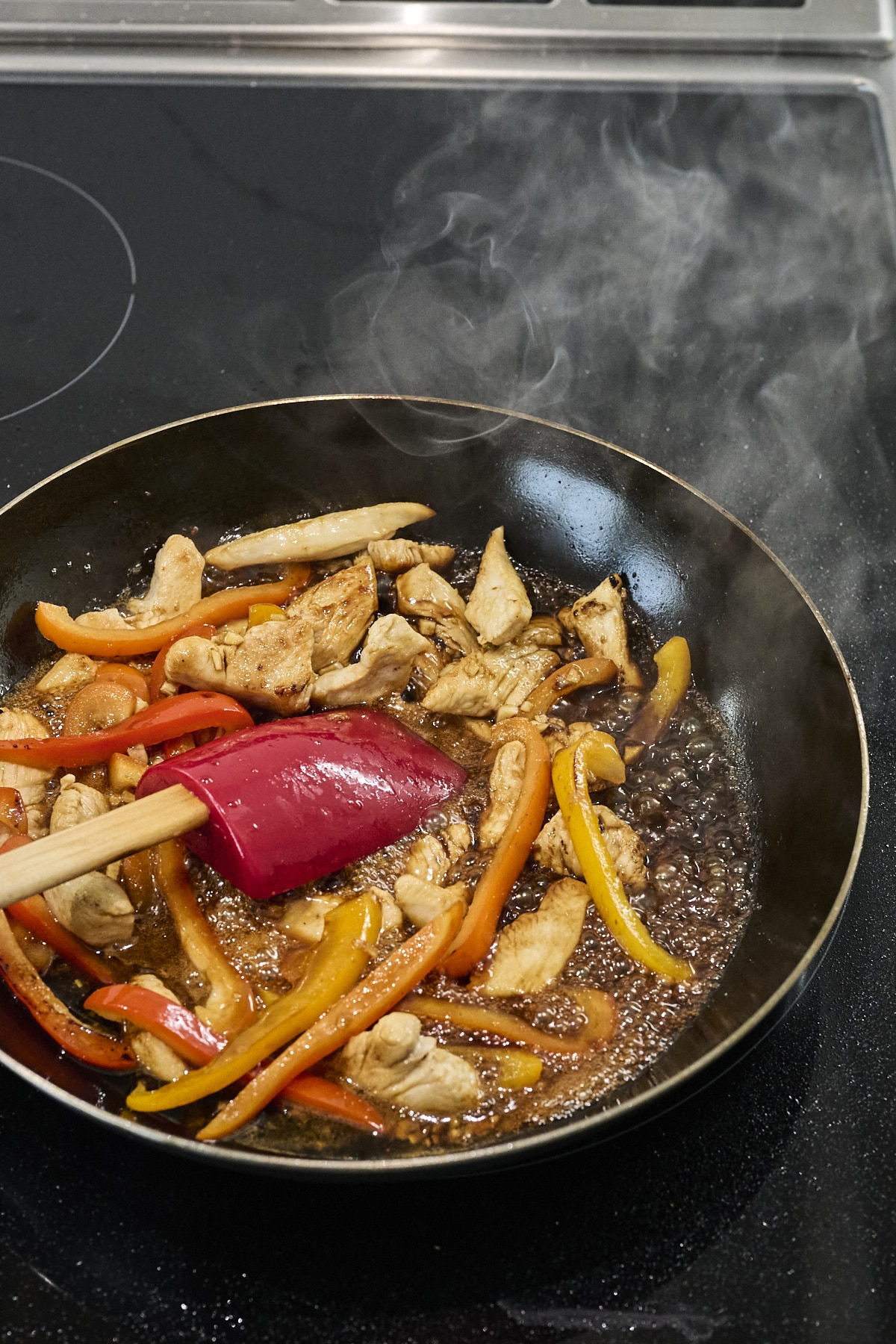 Cashew chicken stir fry with sauce bubbling in pan