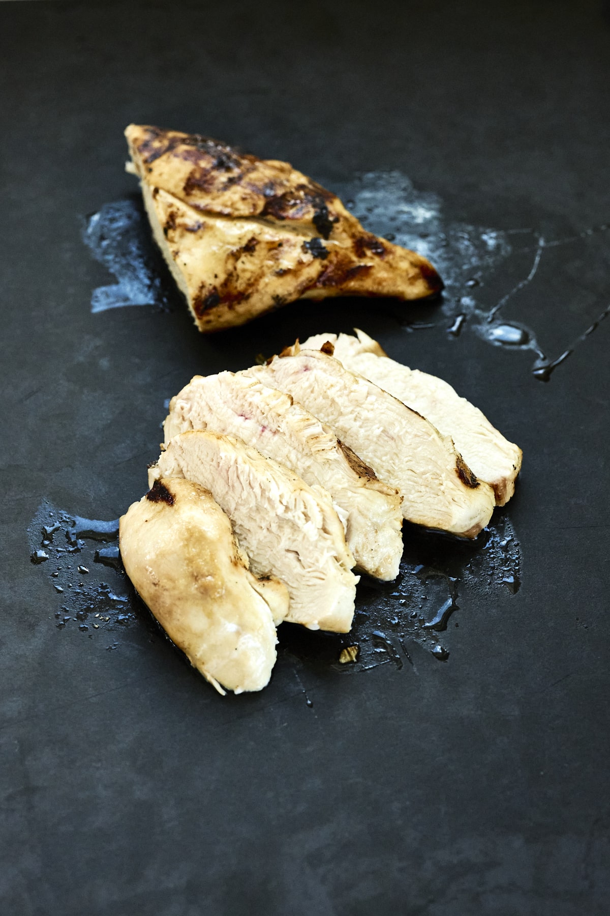 Sliced grilled chicken on a black cutting board