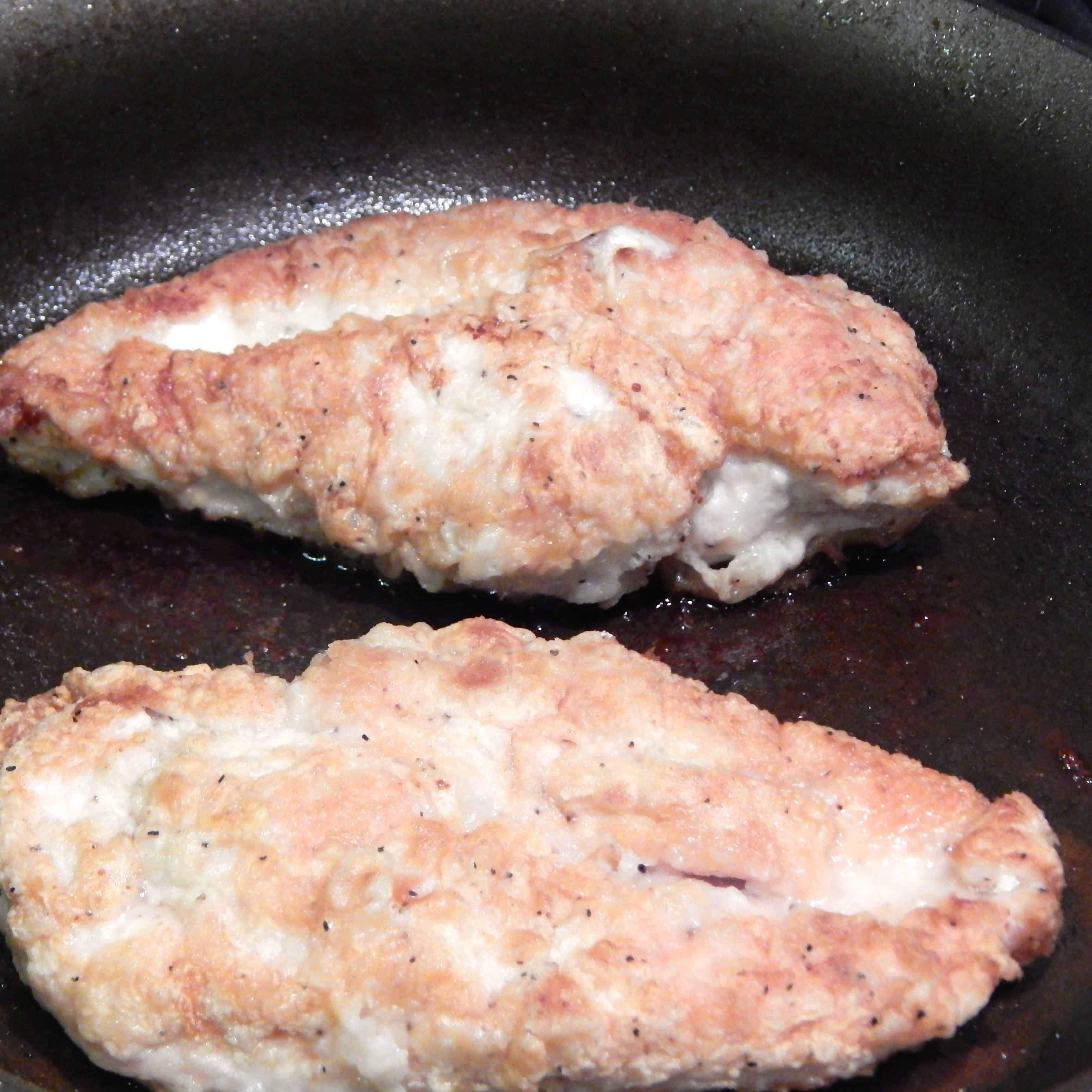 Browned chicken cooking in pan