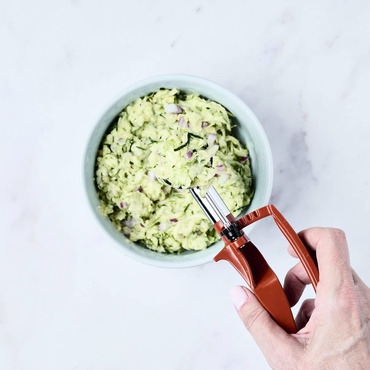 Shredded zucchini for fritters in a bowl