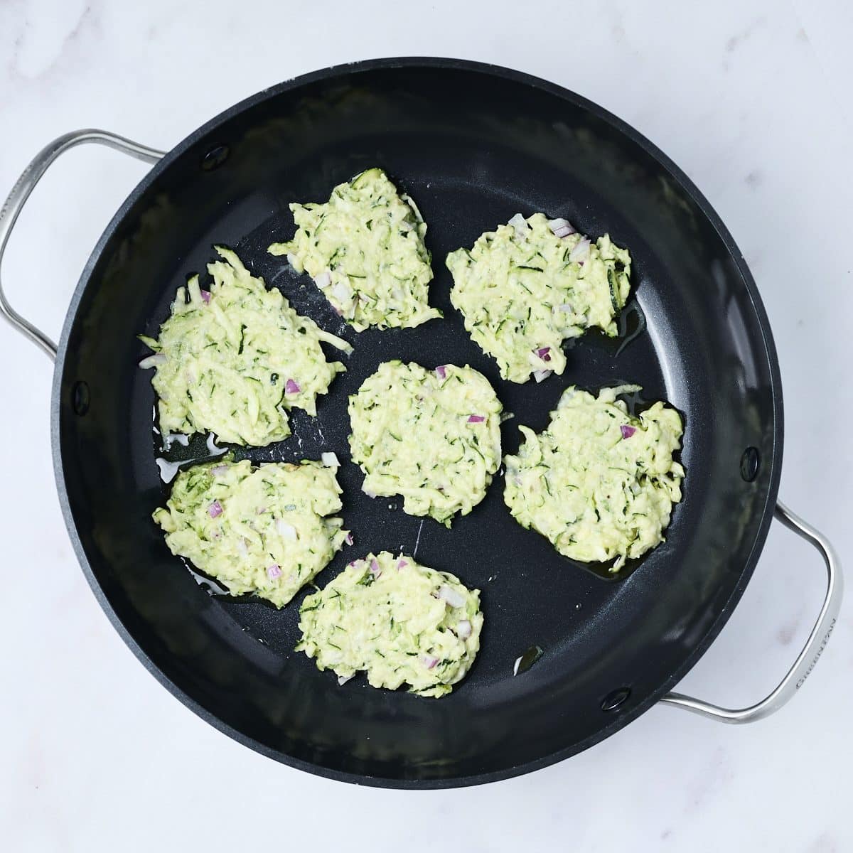 Zucchini fritters being cooked in a pan