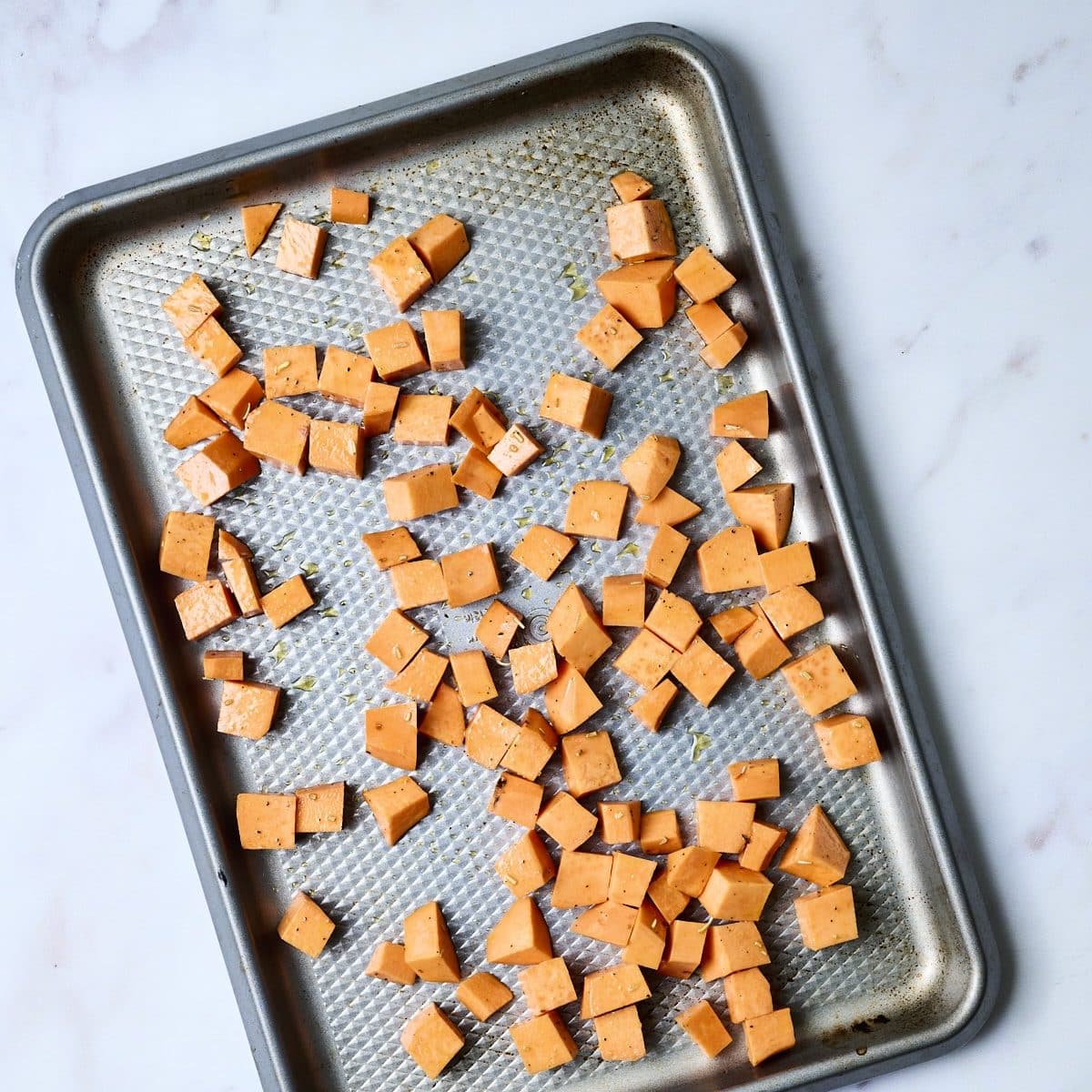 Chopped sweet potatoes on a rimmed baking sheet