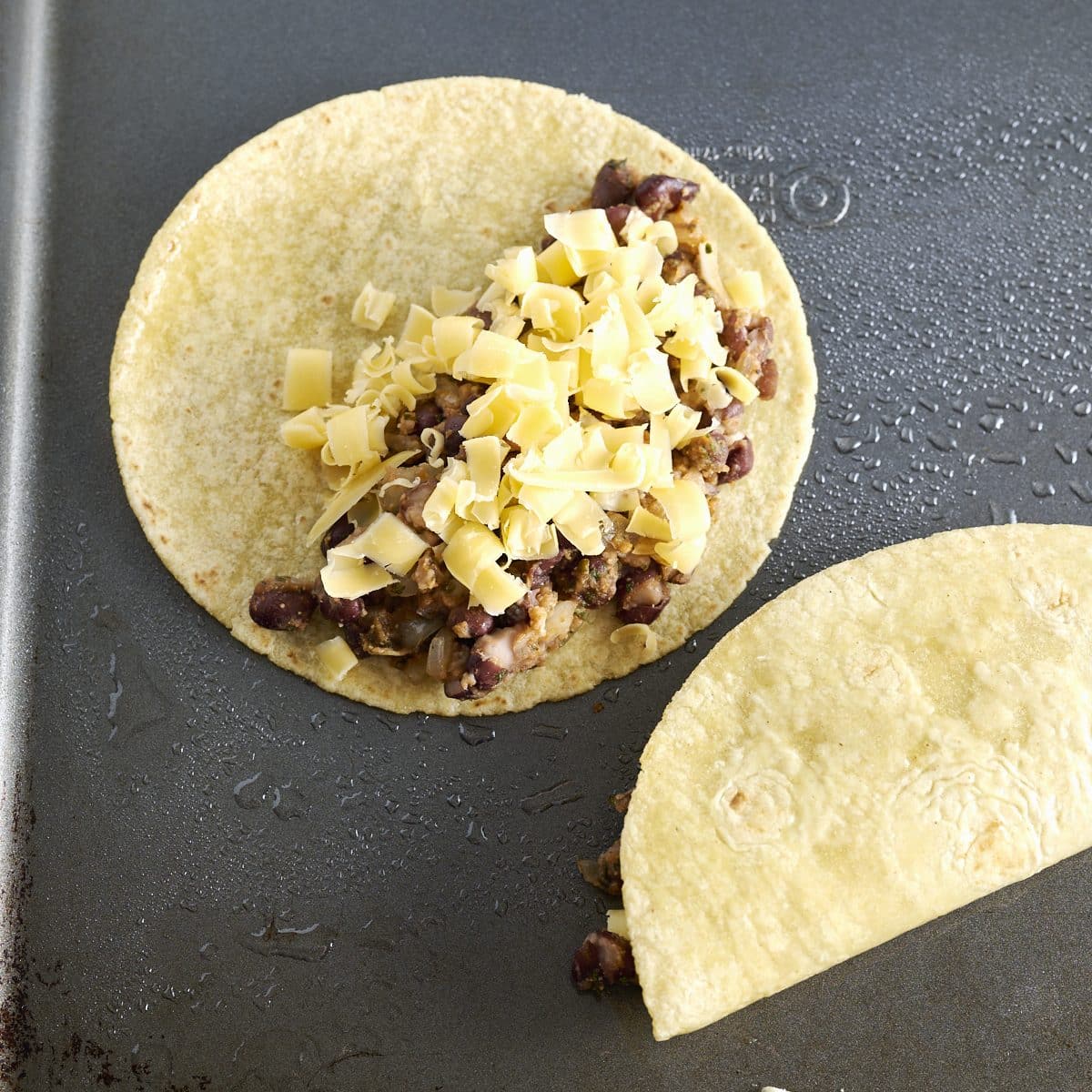 Corn tortillas with black bean taco filling and grated cheese 