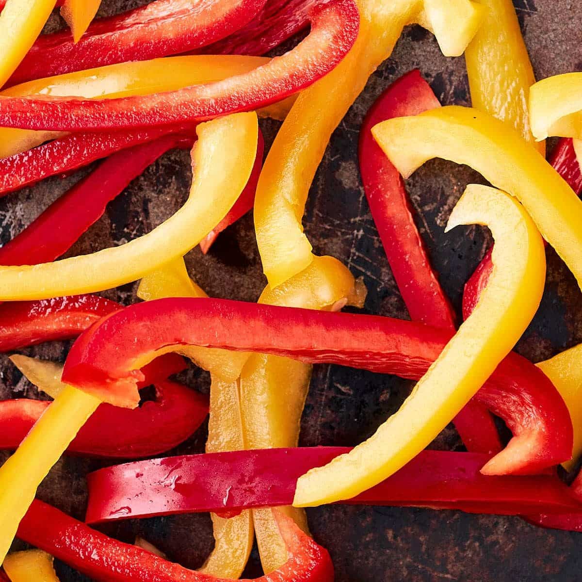 Sliced red and yellow bell peppers on a baking sheet