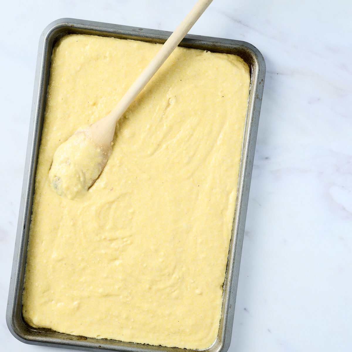 Cornbread mix spread in a quarter sheet pan