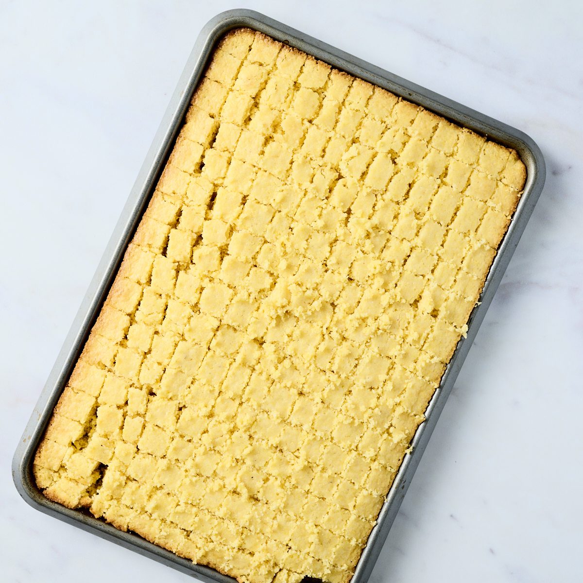 Cooked cornbread in sheet pan sliced into cubes