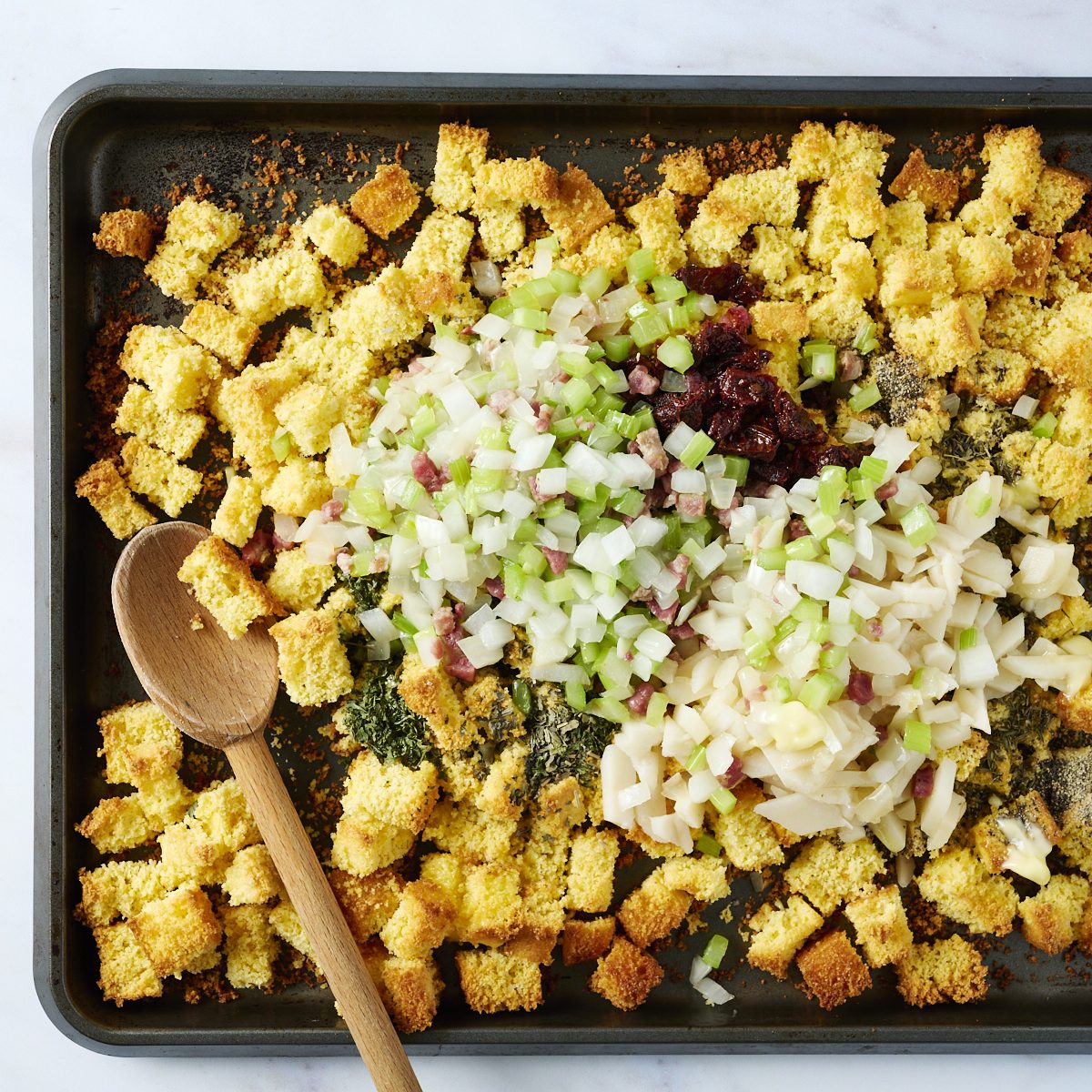 Cornbread cubes, sauted veggies, cooked pancetta and sundried tomatoes on a baking sheet