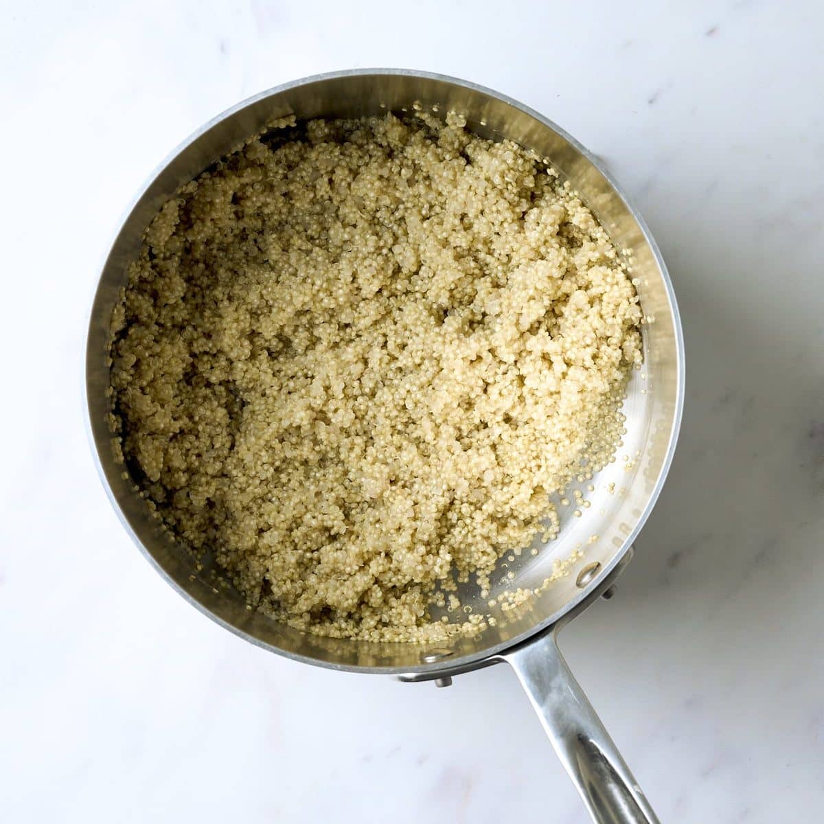 stainless steel sauce pan filled with cooked quinoa
