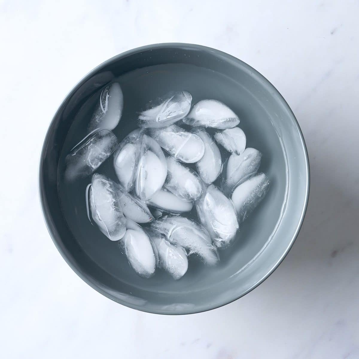 Ice cubes and water in a blue grey bowl