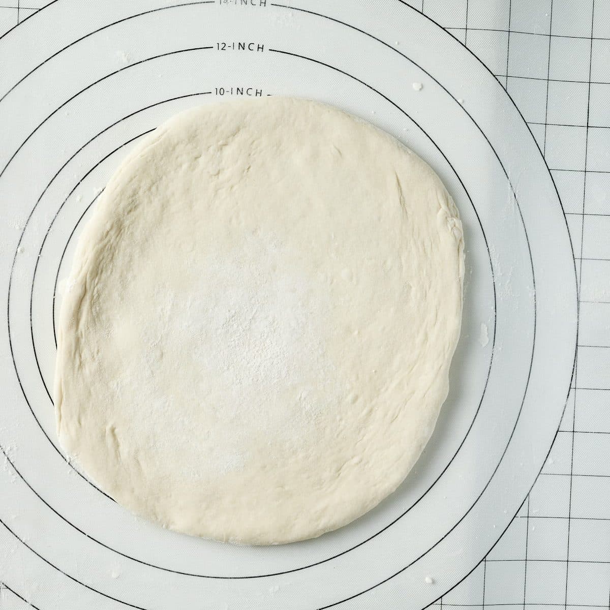 Unbaked pizza dough on rolling mat