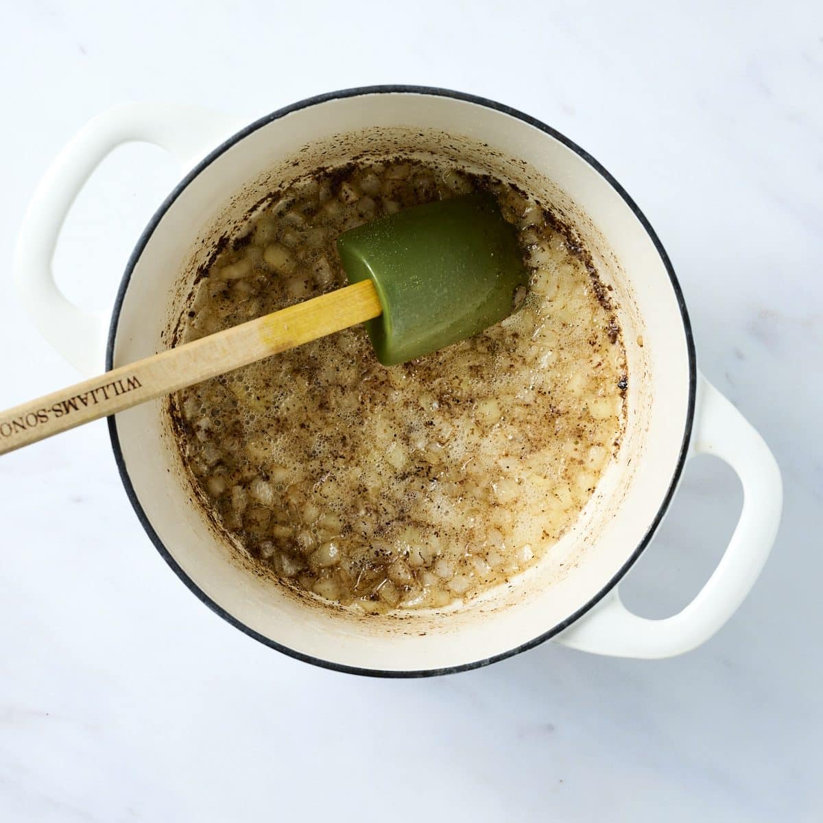 Chopped onions cooking in a white dutch oven