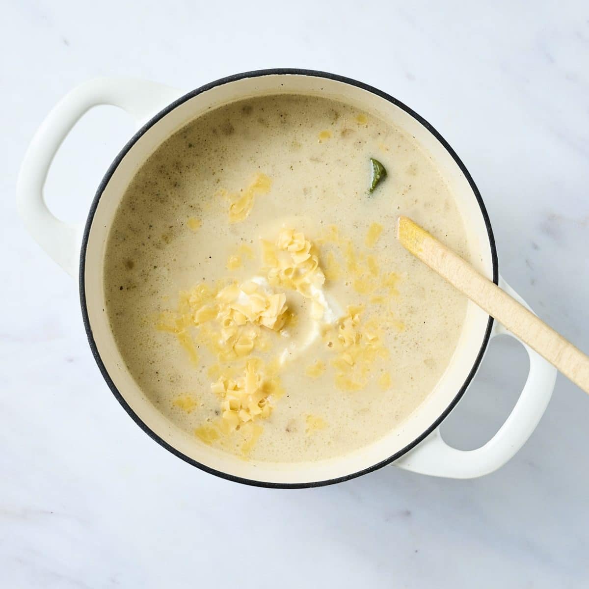 Pot of baked potato soup with shredded cheddar and cream cheese added
