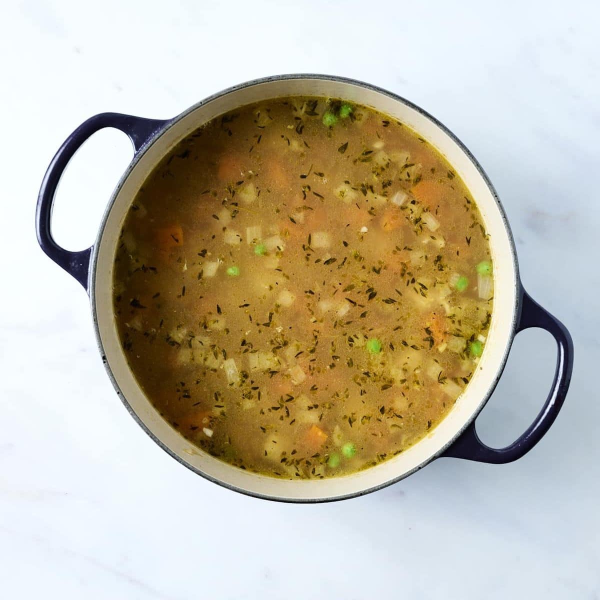 Soup base for dumplings with chicken and peas.