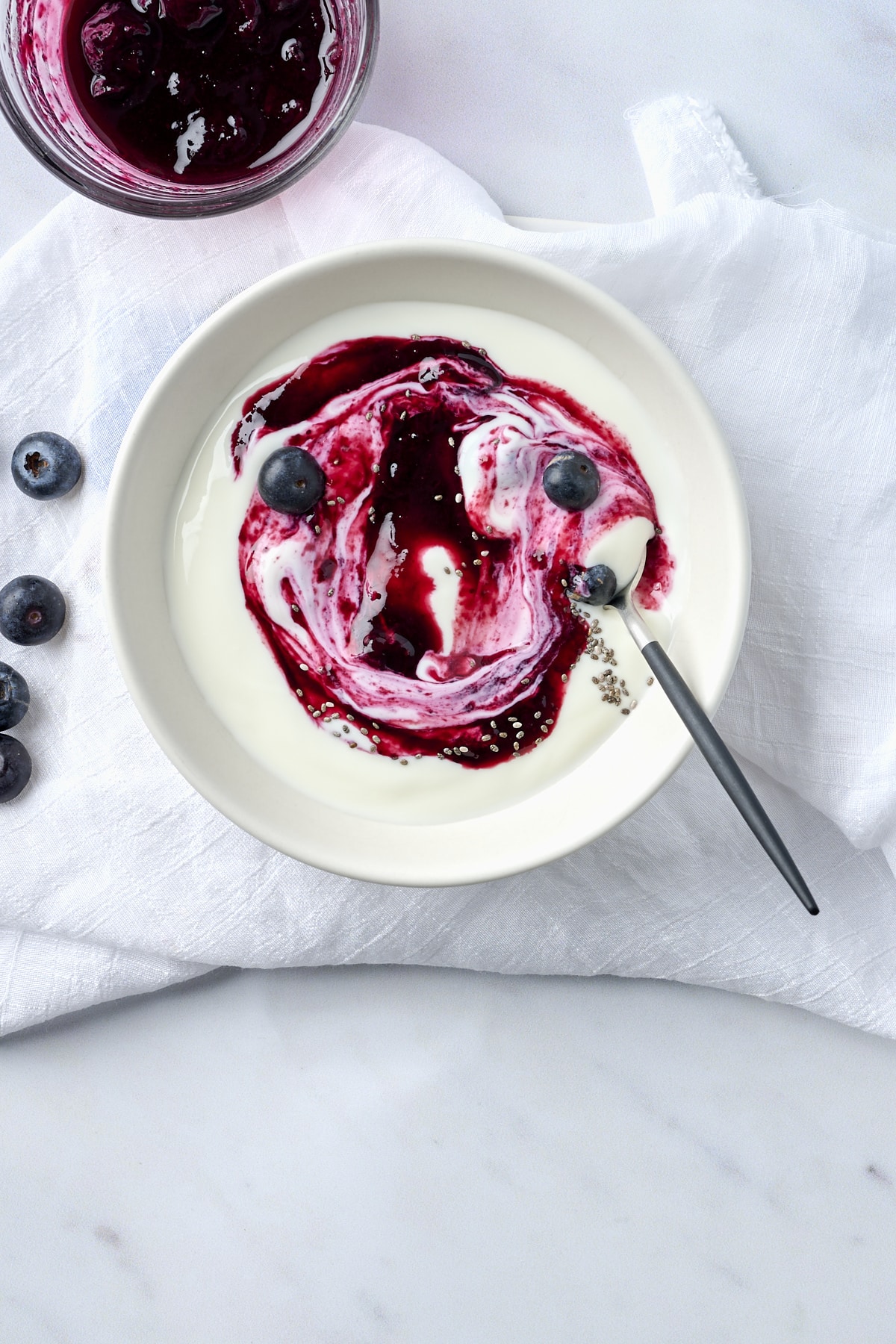 A small bowl filled with greek yogurt with blueberry compote swirled in