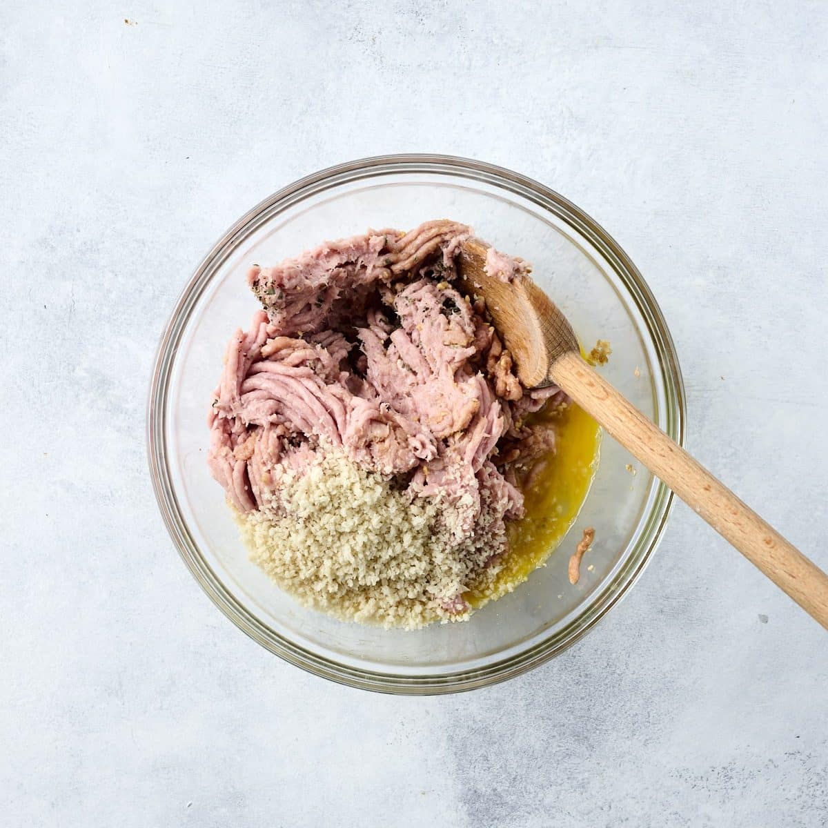 Ground turkey, spices and panko breadcrumbs in a glass bowl