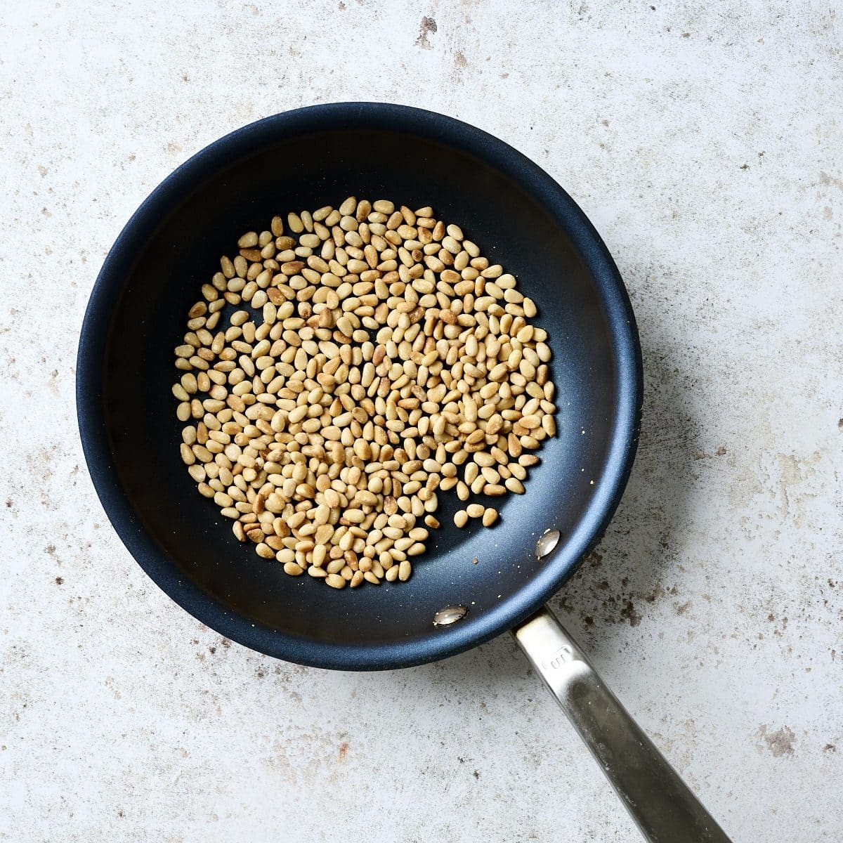 Pine nuts toasting in a small skillet