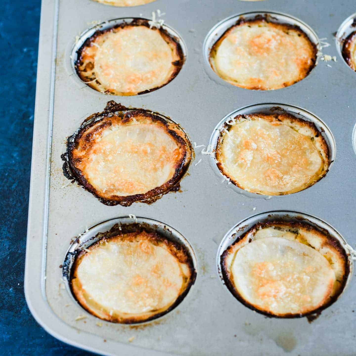 Cooked mini potato gratins cook in a muffin tin.