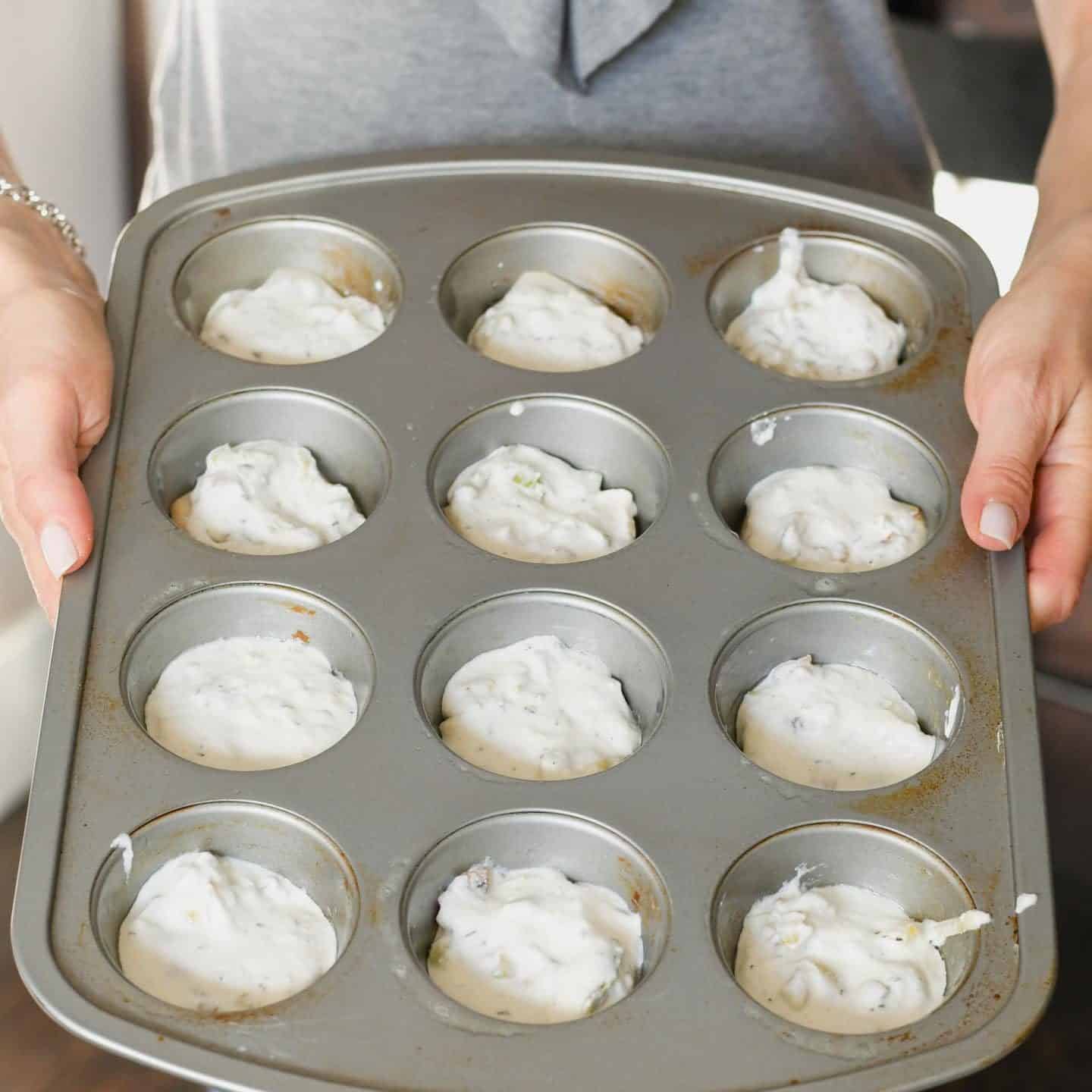 Uncooked mini potato gratins in a muffin tin.
