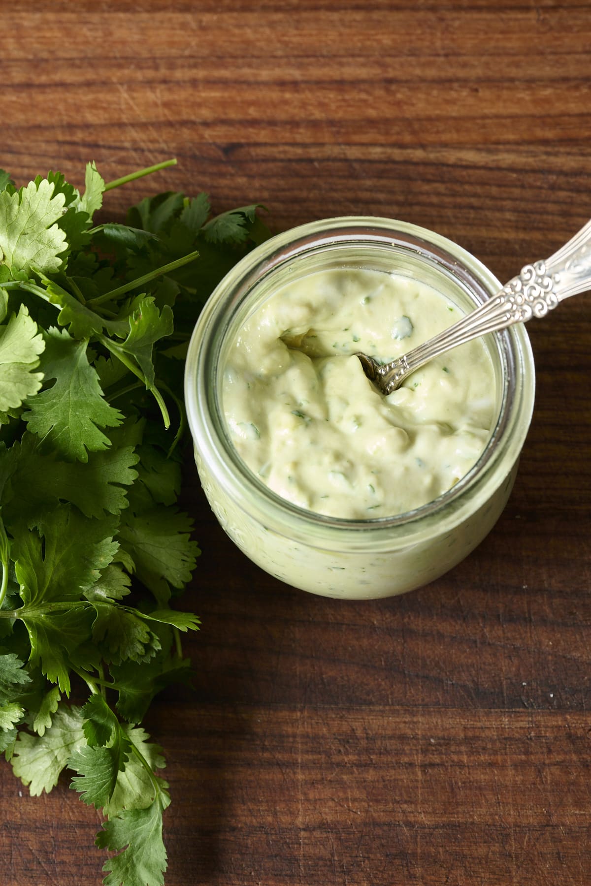 Overhead shot of a glass jar filed with cilantro avocado sauce.