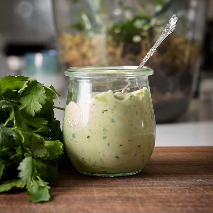 Jar of avocado sauce with a silver spoon in it