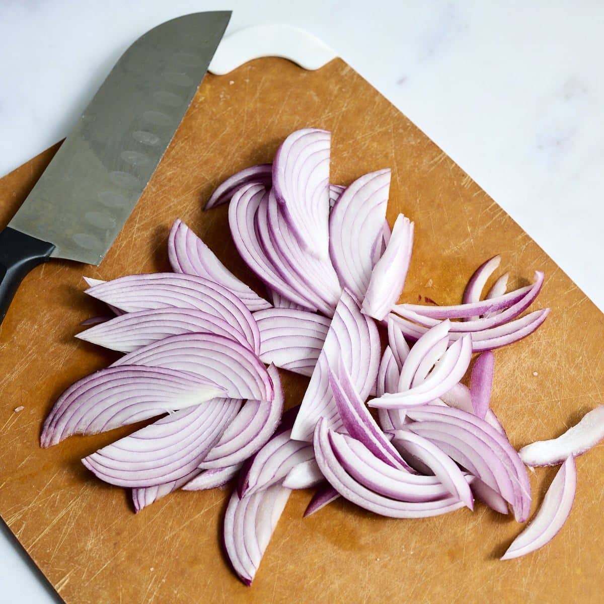 Thinly sliced red onions on a cutting board