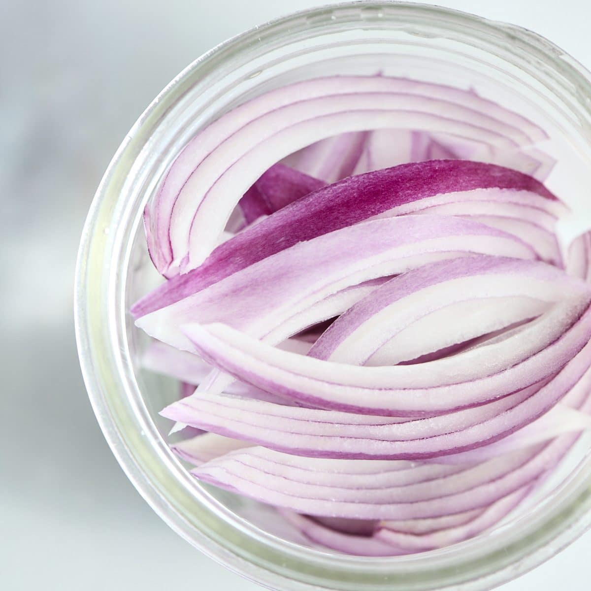 Sliced red onions in a glass jar