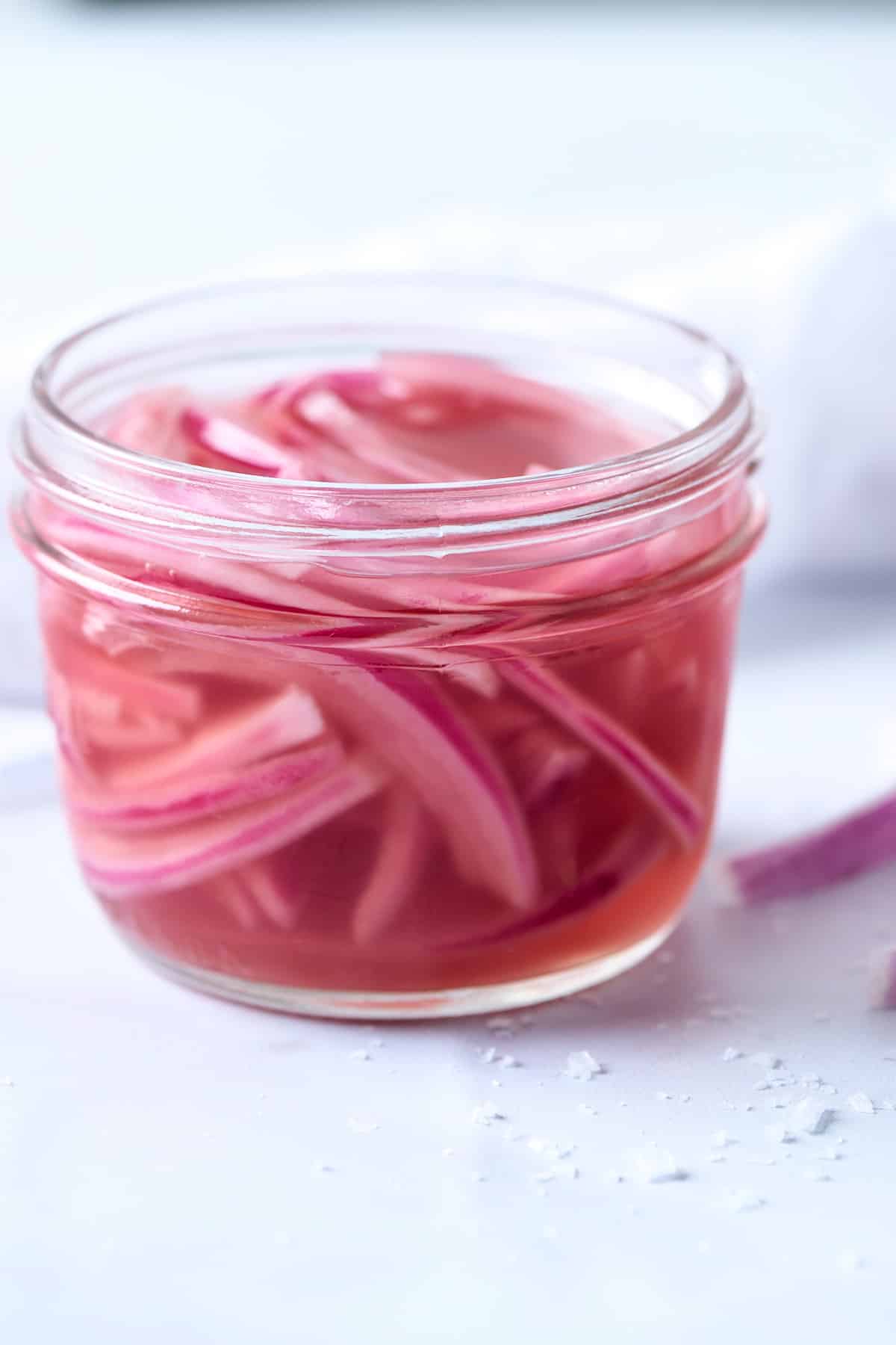 Head on shot of pickled red onions in a glass jar