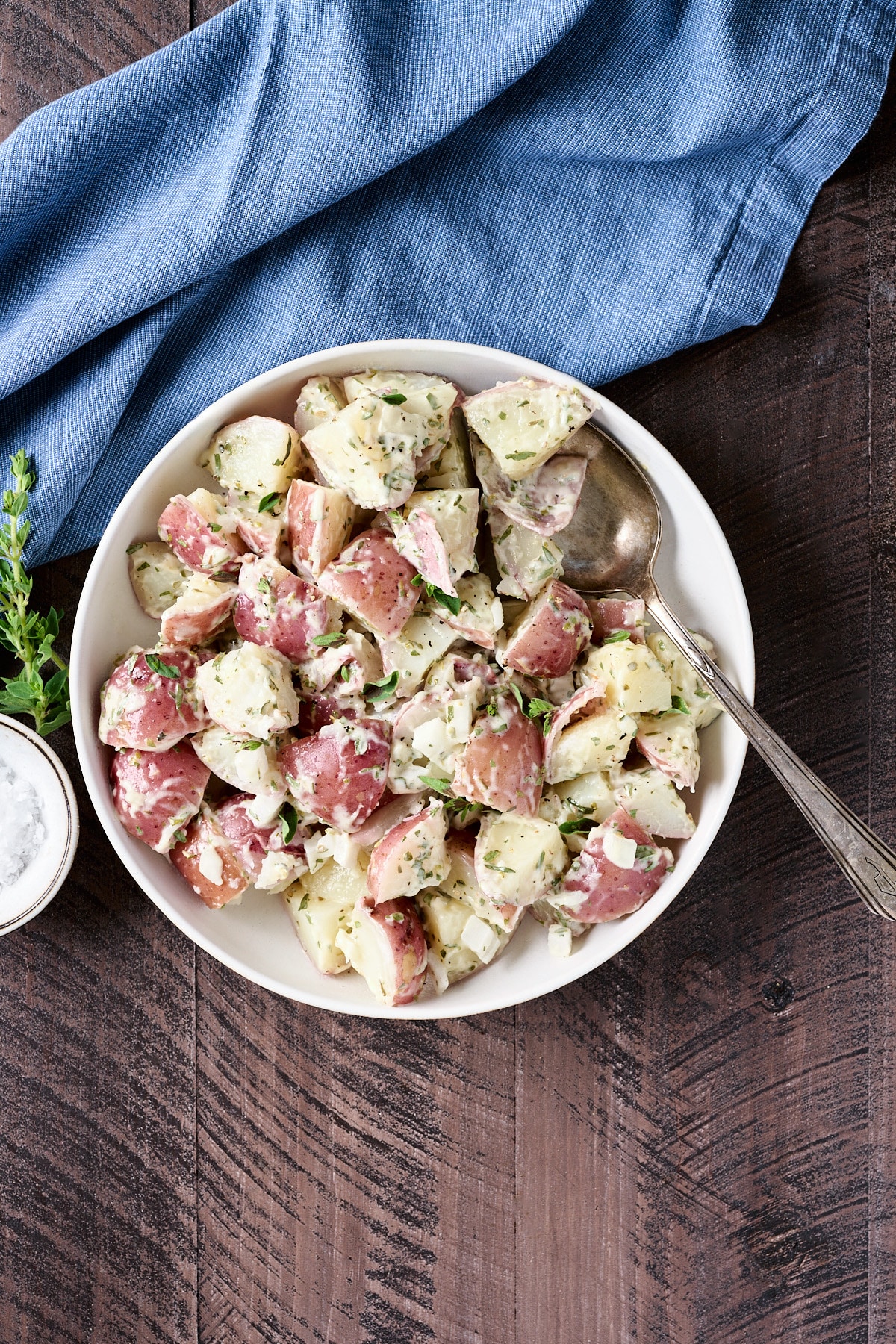 Overhead shot of red skinned potato salad in a cream bowl