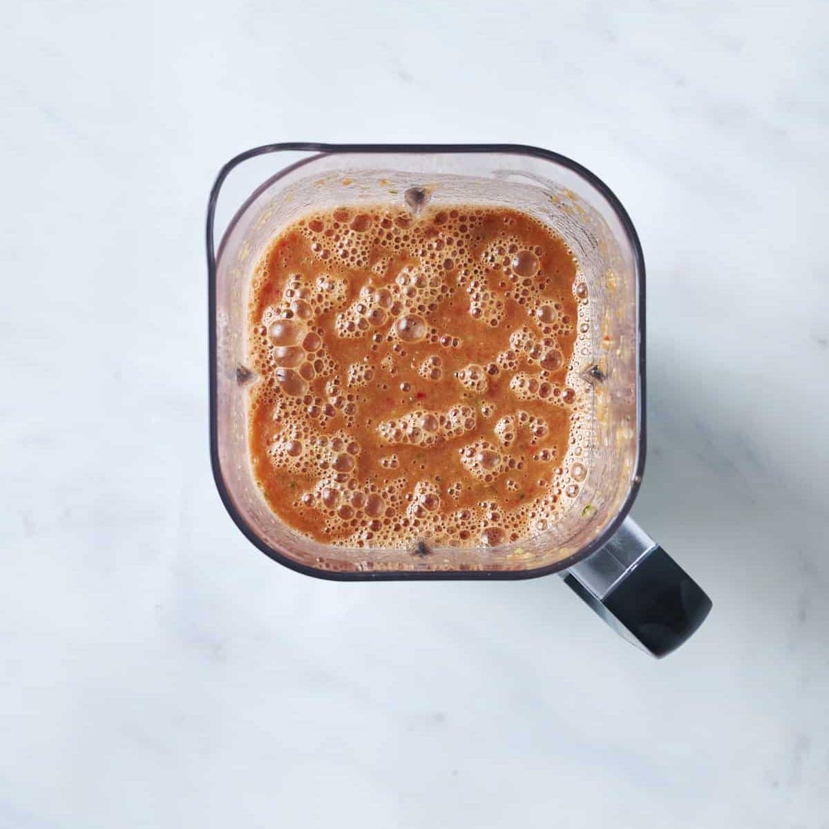 Top-down view of a blender filled with blended tomato gazpacho
