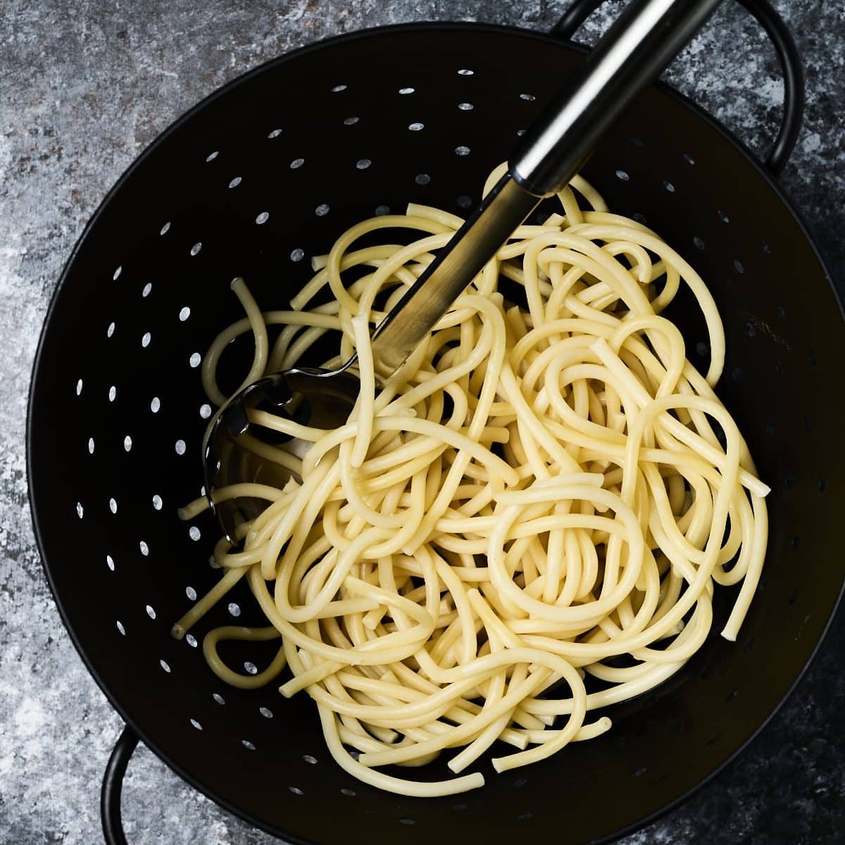 Spaghetti in a black pasta drainer